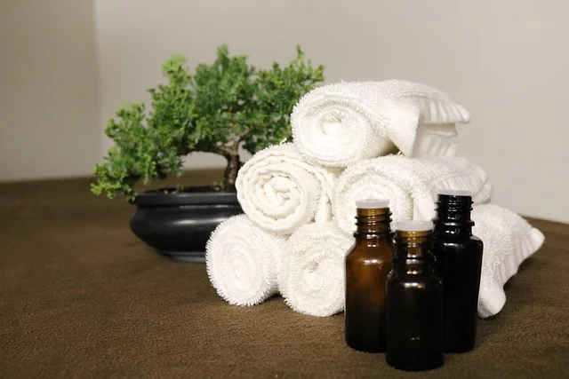 faux bonsai tree in a spa setting with rolled white towels and essential oils