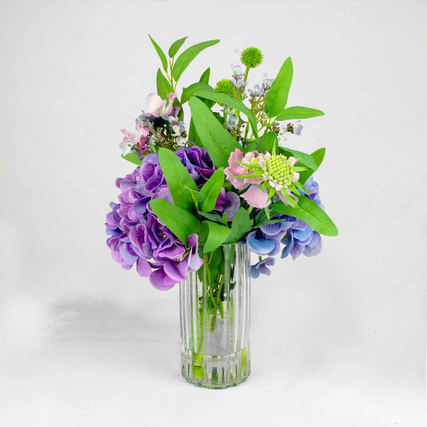 HYDRANGEA BLUE AND PURPLE WITH FOLIAGE IN RIBBED RECT VASE