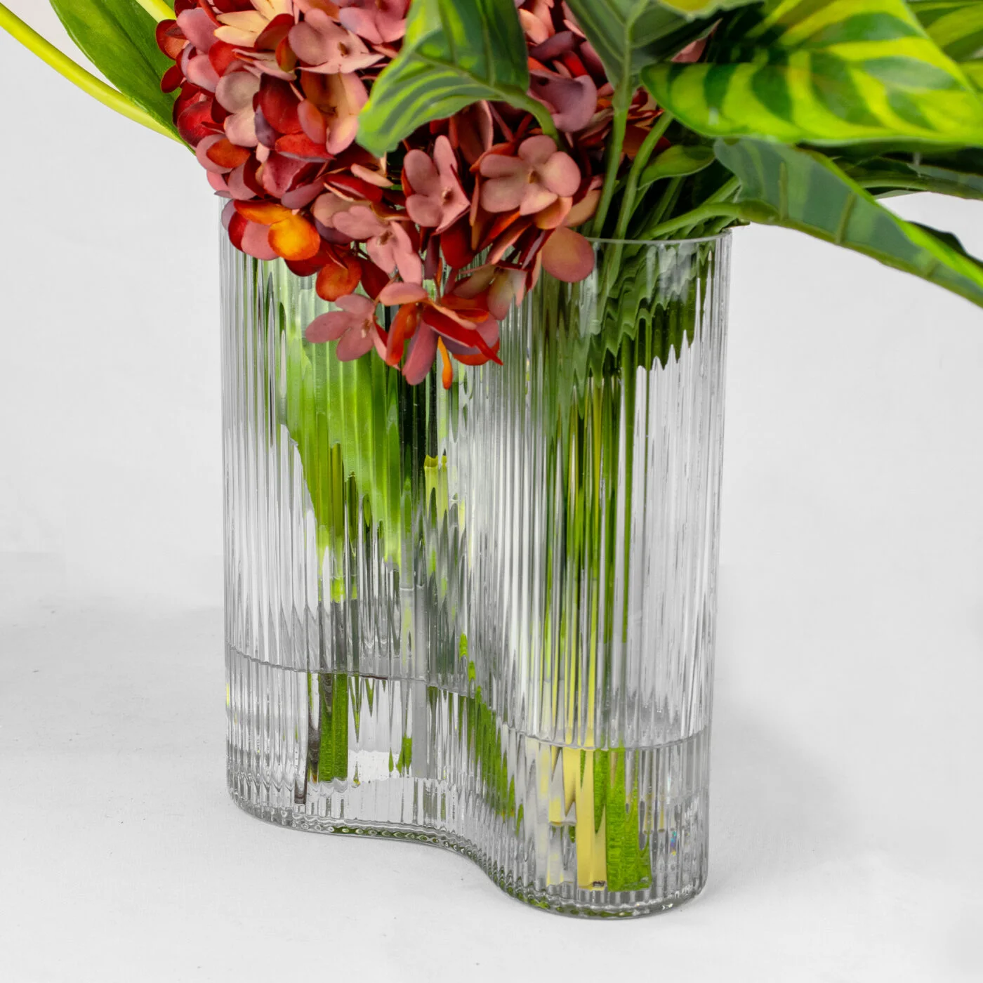 TULIPS ORANGE WITH CYMBIDIUM ORCHID AND FOLIAGE IN CURVE VASE
