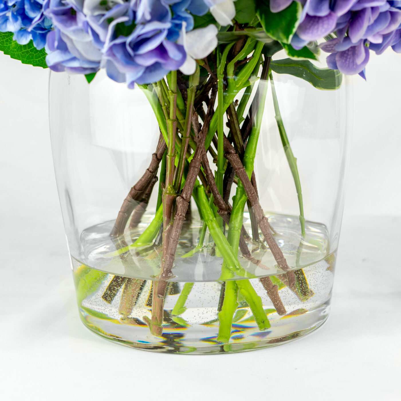 MIXED BLUE HYDRANGEAS IN BARREL VASE