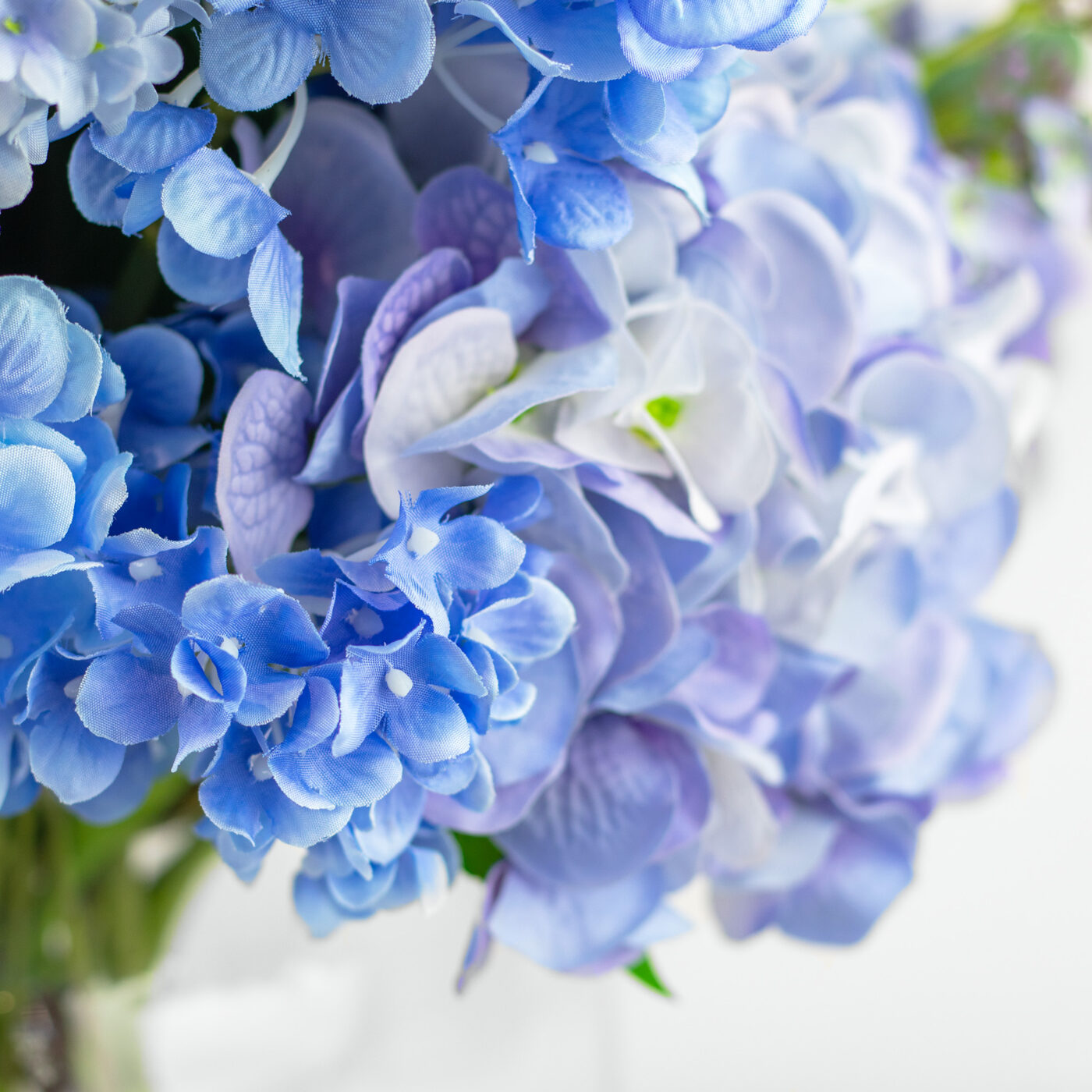 MIXED BLUE HYDRANGEAS IN BARREL VASE
