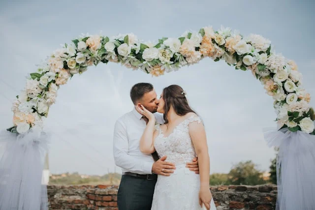 wedding arches - married couple kissing in front of a wedding arch