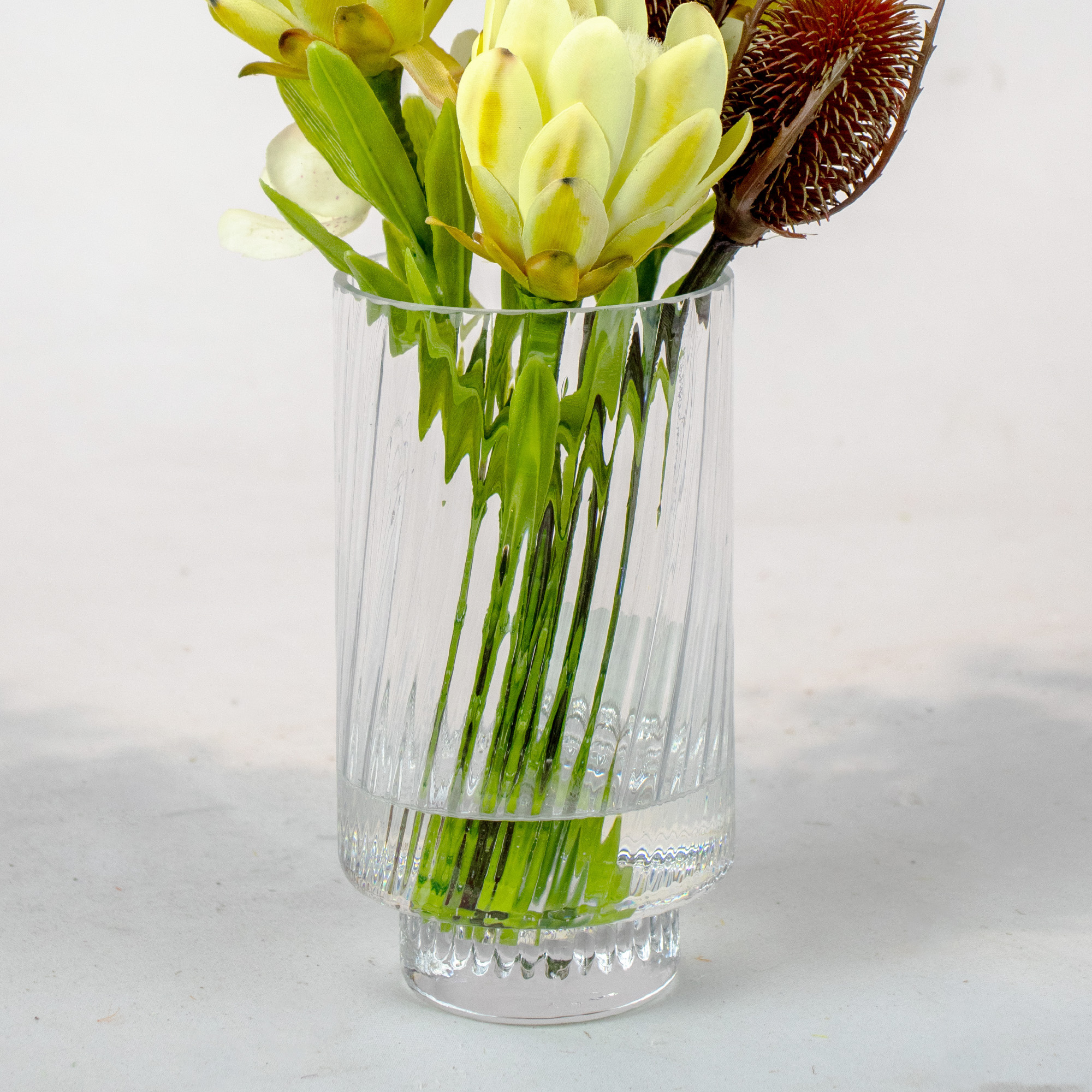 GREEN PROTEA, CONFETTI ORCHID & BANKSIA IN RIBBED GLASS VASE
