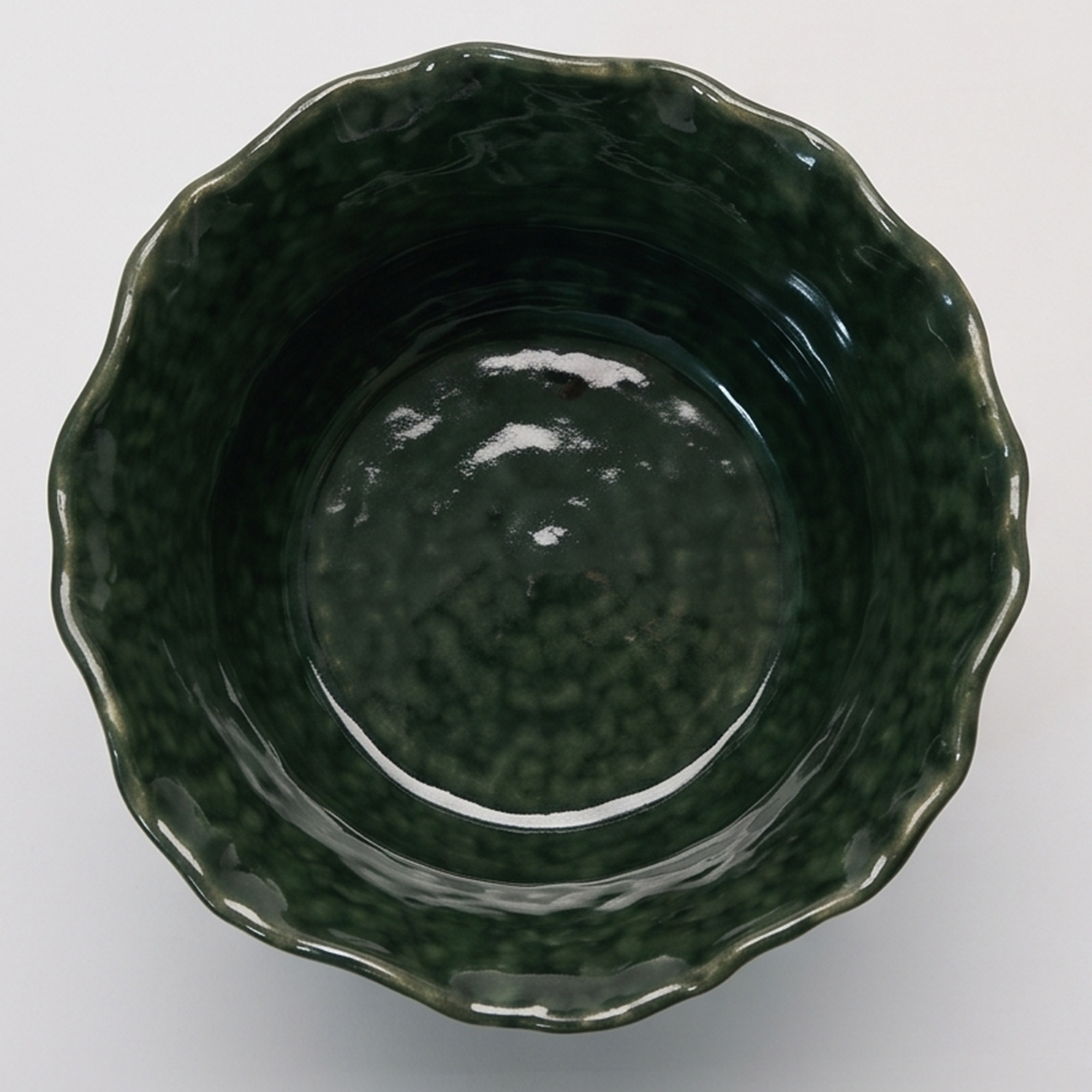 Medium 21.5cm emerald green scalloped ceramic bulbous pot with a fluted rim styled on a wooden entryway console.