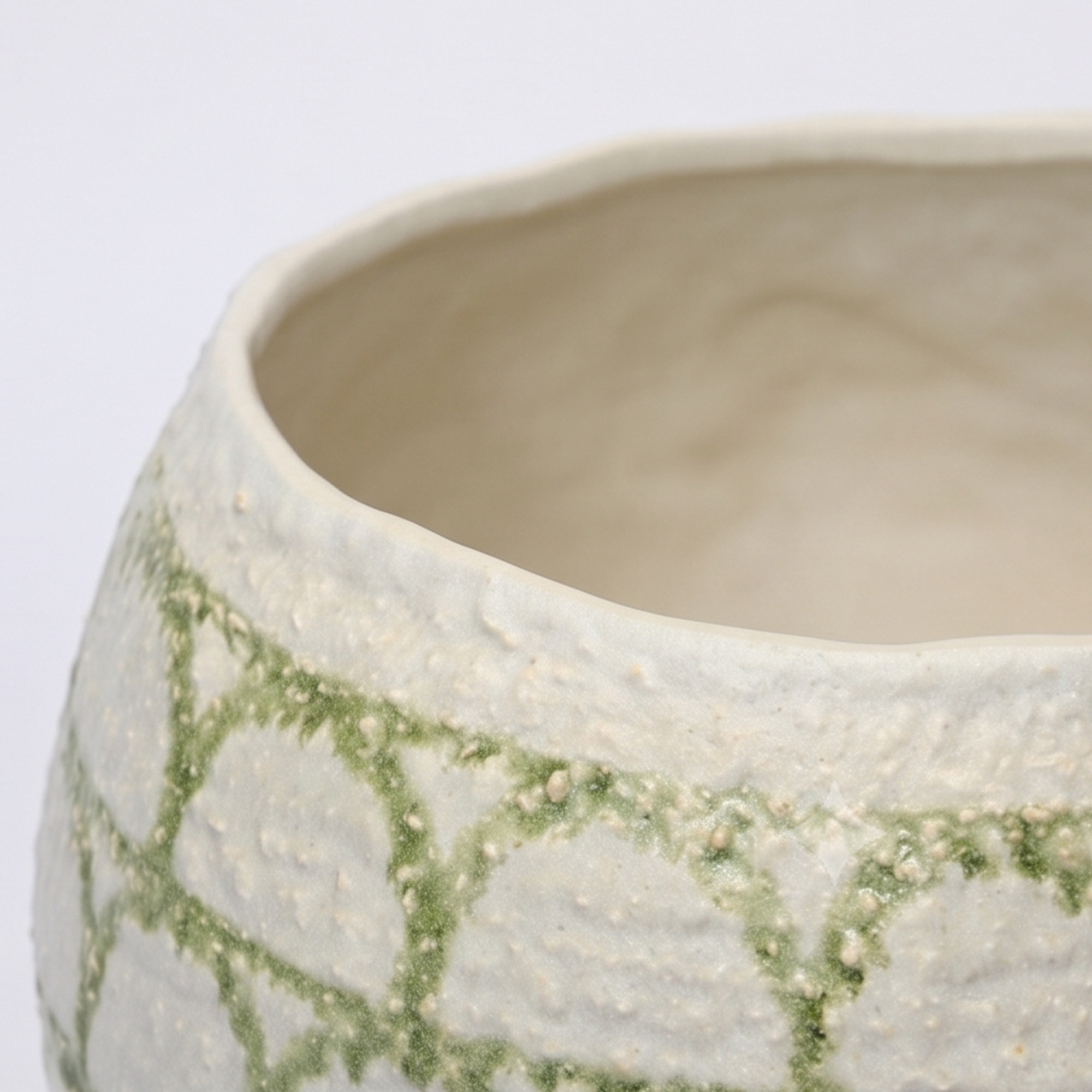 Large 31.5cm matte arch pattern green and white ceramic pedestal bowl vase styled on a wooden dining room sideboard.