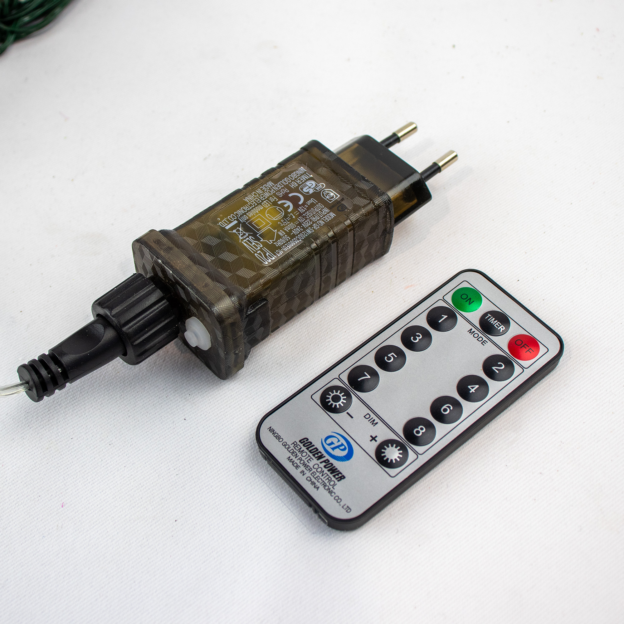 600 warm white LED Christmas tree curtain lights on a green cord with a remote control and power adapter.